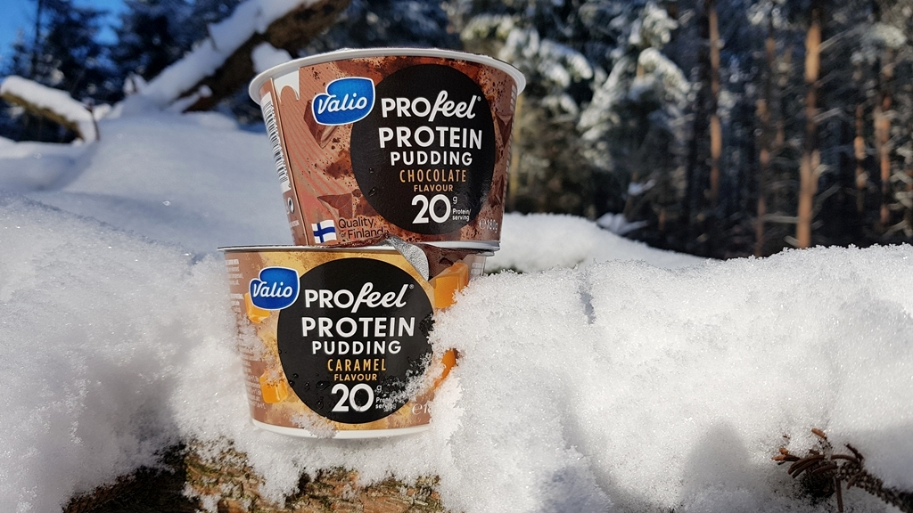 Valio pudding proteinowy (czekoladowy i karmelowy) na tle śniegu w lesie